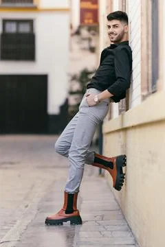 Man posing with foot and back against a street wall Stock Photos