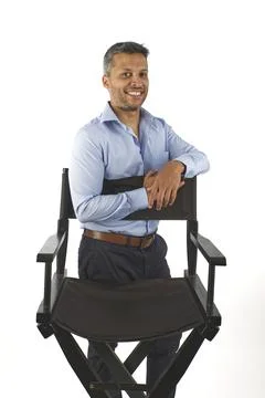 A man is posing in front of a chair Stock Photos