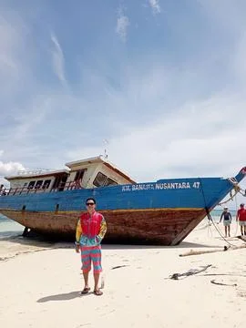 A man posing in front of an old boat at Maluku Stock Photos