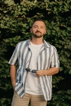A man is posing in the garden. A guy with green leaves in the background. Stock Photos