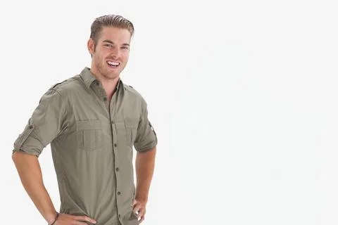Man posing hands-on-hips, smiling at camera in studio wearing olive shirt, Foto stock