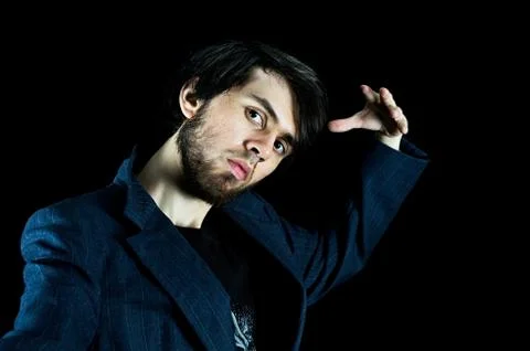 Man posing with his left hand up, tilting his head Stock Photos