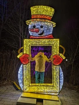 Man Posing Inside Giant Illuminated Snowman Photo Frame Prop at Night Festiva Stock Photos