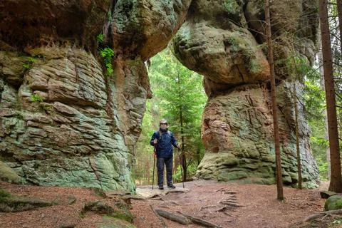 Man posing on natural stone gate in Stolowe Mountains Fotos Stock