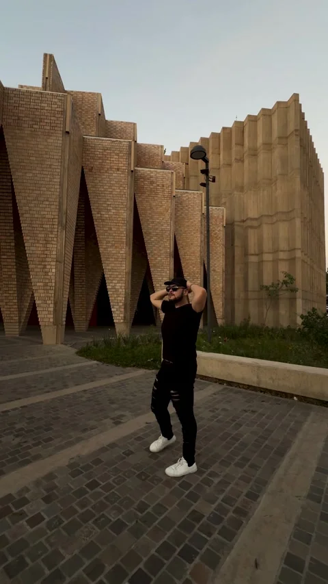 Man posing near geometric modern architecture in urban evening setting Stock Footage 299818911