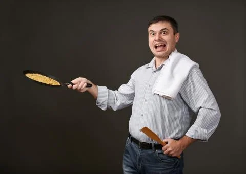 Man posing with a pancake in a pan, white shirt and pants, gray background, s Foto stock