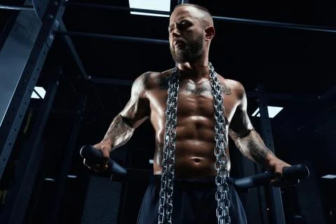 Man posing on parallel bars in gym. Stock Photos
