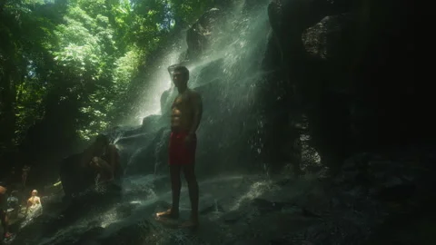 Man posing at Tukad Cangkir Waterfall, Bali Stock Footage 218457245