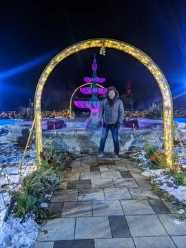 Man Posing Under Illuminated Archway In Front of Purple Fountain at Night Stock Photos