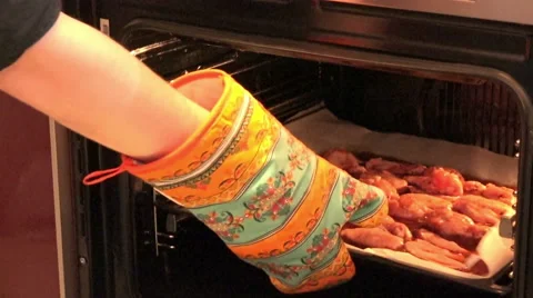 Man with a potholder puts baking chicken in the oven Stock Footage 47326429