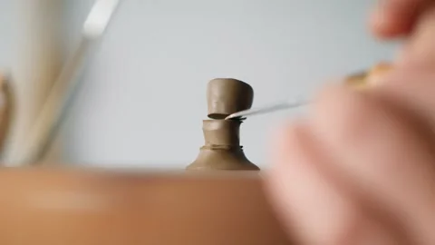 A man potter cuts the handle for the lid of a clay teapot with a knife. craft Stock Footage 145534534