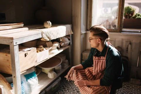 Man potter looking for ware for a work. Young man potter in his workshop Stock Photos