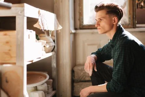 Man potter looking for ware for a work. Young man potter in his workshop 写真素材