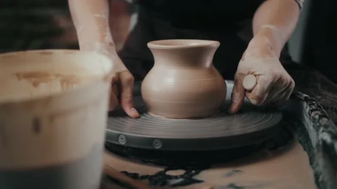 Man potter working on potters wheel making ceramic pot from clay in pottery Stock Footage 150000591