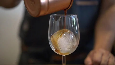 Man pour black coffee from copper cup into wine glass, home brewing style Stock Footage 108252552