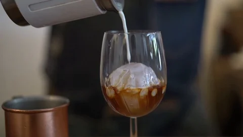 Man pour milk into black coffee in wine glass, home brewing style Stock-Footage 108252553