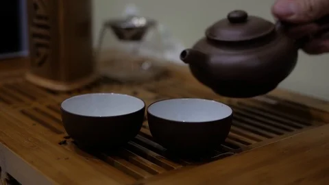 Man pour tea from an earthenware teapot into bowls. Chinese tea ceremony Stock Footage 99573054