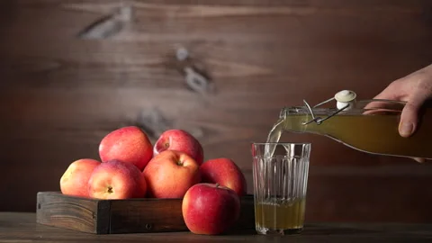 Man pouring apple cider from bottle into glass next to fresh red apples Stock Footage 304515831