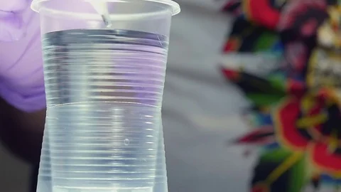 Man pouring black paint in a plastic cup with water close-up Stock Footage 73139028