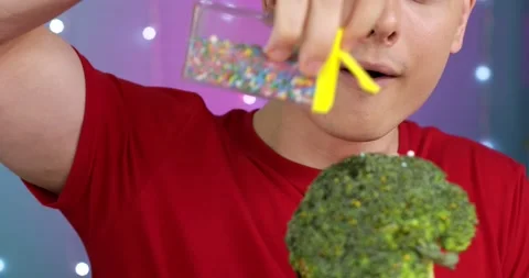 A man is pouring candy onto green broccoli Stock Footage 166555000