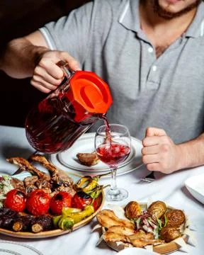 Man pouring cherry compot served with kebab platters Stock Photos