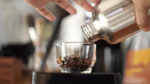 Man pouring coffee beans to small cup to scale them before grind, coffee brewing Stock Footage 219992050