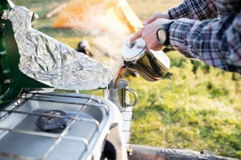 Man pouring coffee in cup while camping Foto stock