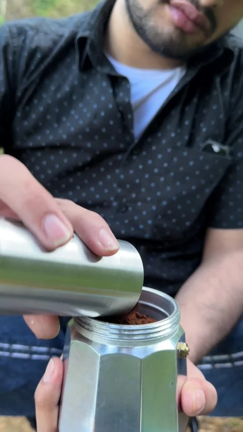 Man Pouring Coffee Grounds into Moka Pot Outdoor Close-up Vertical Shot Stock Footage 323907243