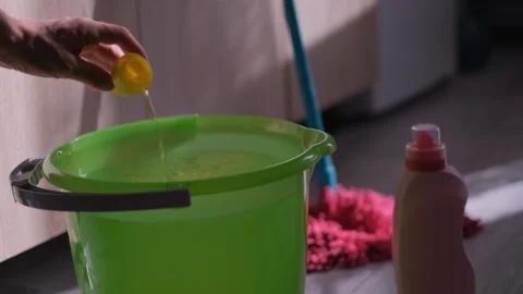 Man pouring floor cleaning liquid into a bucket of water, close-up Stock Footage 301649331