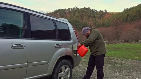 Man pouring gasoline into an empty fuel tank from a plastic red gas can Видео 224063619