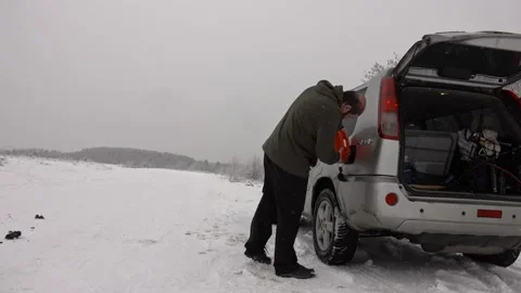 Man pouring gasoline into an empty fuel tank in winter offroad adventure Stock Footage 231897732