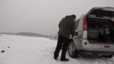 Man pouring gasoline into an empty fuel tank in winter offroad adventure Stock Footage 231897771