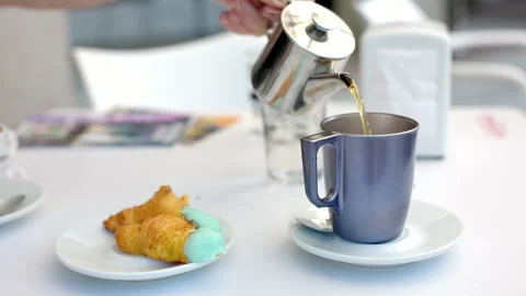 Man pouring hot tea into a cup on a table on a cafeteria terrace Stock Footage 245265357