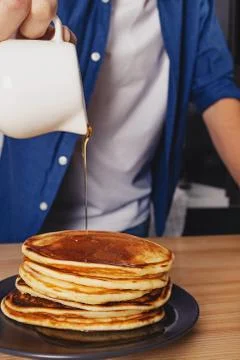 Man pouring with maple syrup on the stack of pancakes Stock Photos
