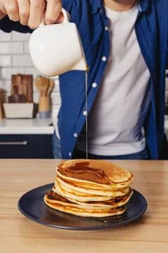 Man pouring with maple syrup on the stack of pancakes Stock Photos