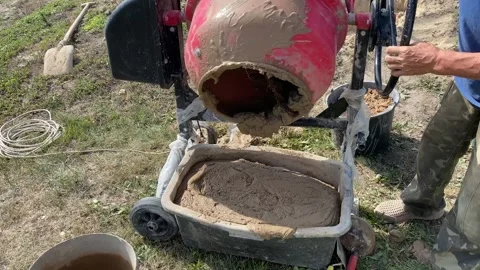 Man pouring mixed clay from red concrete mixer into container Stock Footage 316539708
