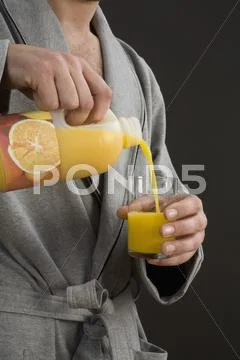 A man pouring orange juice into a glass, midsection Stock Photos