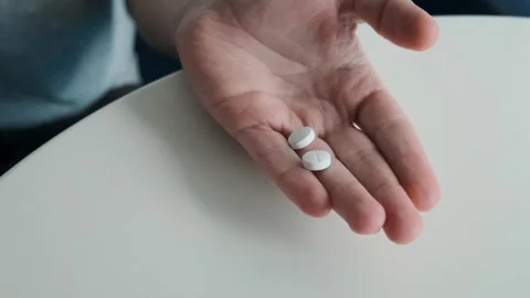 Man pouring painkiller white tablets in male hand from medicine bottle. Palm of Stock Footage 315860185