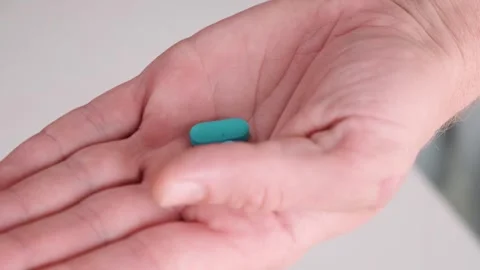 Man pouring a PrEP blue pill from medical bottle in a hand. HIV prevention using 動画素材 252040789