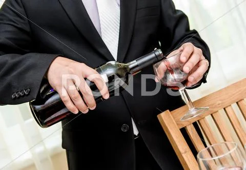 Man pouring red wine from bottle into a glass Stock Photos