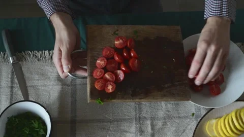 Man pouring sliced cherry tomatoes into a bowl Vidéo 319932827