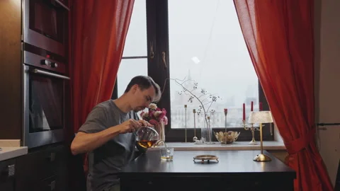 Man pouring tea while sitting at a table by the window Stock Footage 295171808