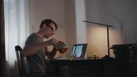 Man pouring tea while working at home desk Stock Footage 315959204