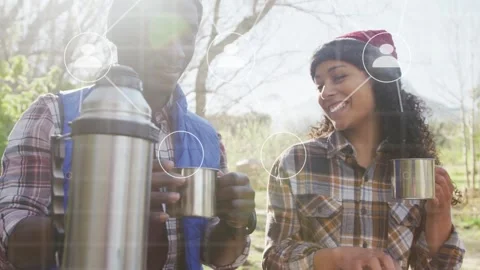 Man pouring thermos to share hot drink while woman holding map, tech overlay Stock Footage 333774683