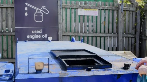 Man pouring used engine oil into recycling hopper uk Stock Footage 114565128