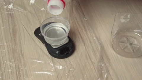 Man pouring a viscous liquid into a plastic container on electronic scale. Video stock 153547506
