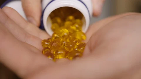 Man Pouring Vitamine D3 Capsules to Hand, Close up. Omega 3 Gold Fish Oil Cap Stock Footage 129597084