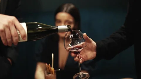 A man is pouring wine into a glass while another man watches Stock Footage 295996878