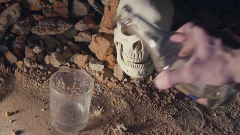 Man pours alcohol and drinks on the background of the skull. alcohol addiction 스톡 동영상 83418600