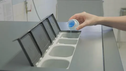 Man pours blue liquid laundry detergent into compartment of washing machine Stock Footage 202374536